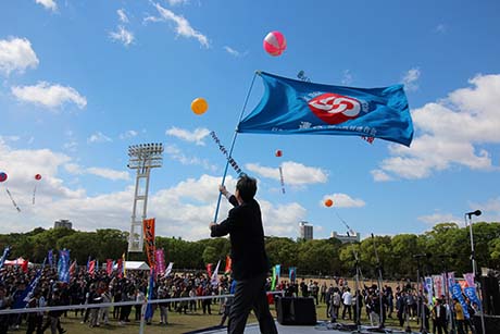 オープニングセレモニーで構成組織や各種委員会の組合旗が壇上に結集。連合大阪の旗が青空にたなびく